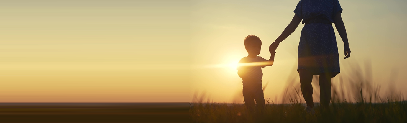 Caregiver and child holding hands outdoors