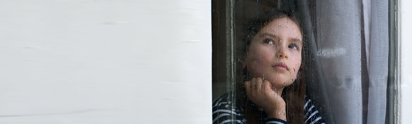 Child looking out rainy window